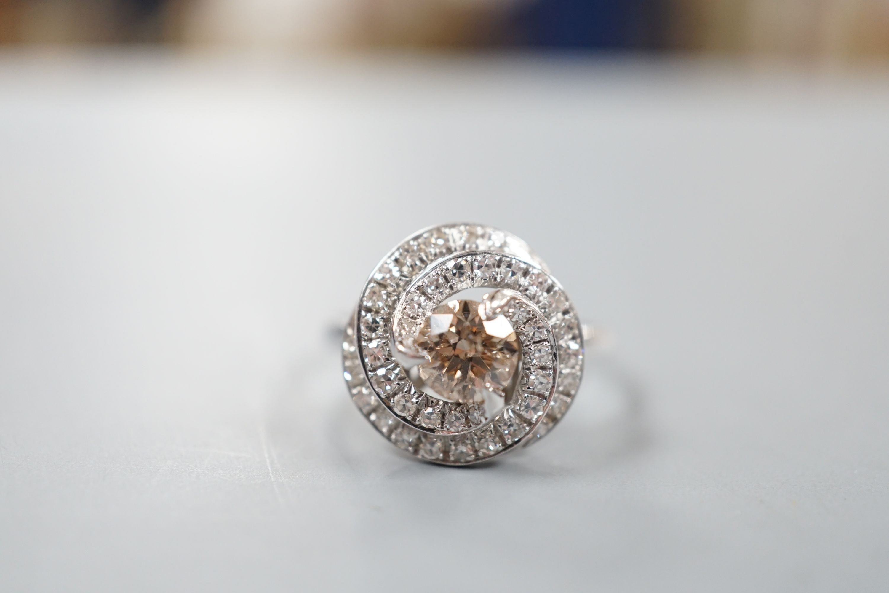 A French white metal(18ct poincon mark) and cognac coloured single stone diamond ring, with diamond set spiral cluster setting, size S, gross 5.5 grams.